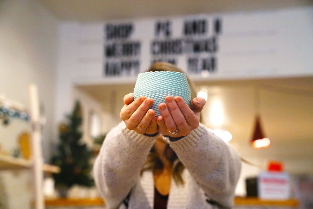 Samantha Fisher holding locally made ceramics up in front of her face
